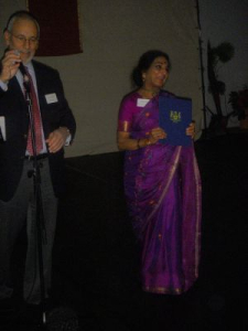 Menaka Thakkar accepting a congratulatory scroll from Peter